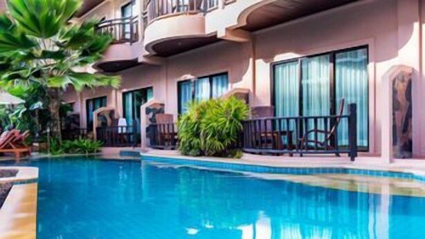 A hotel with a swimming pool, outdoor seating, and a balcony with a view of the pool. - Nipa Resort (Phuket)