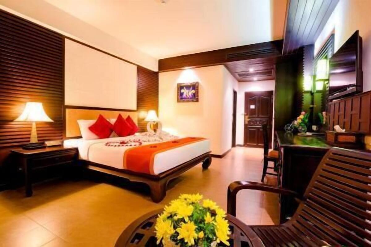 Une chambre d’hôtel comprenant un lit, des tables de chevet, un bureau, une chaise et un téléviseur.