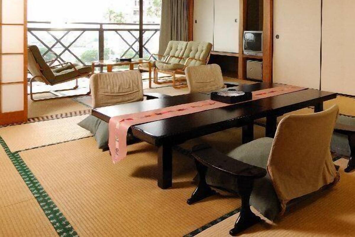 Una tradizionale stanza giapponese con pavimento in tatami, un tavolino basso, sedie e porte scorrevoli.