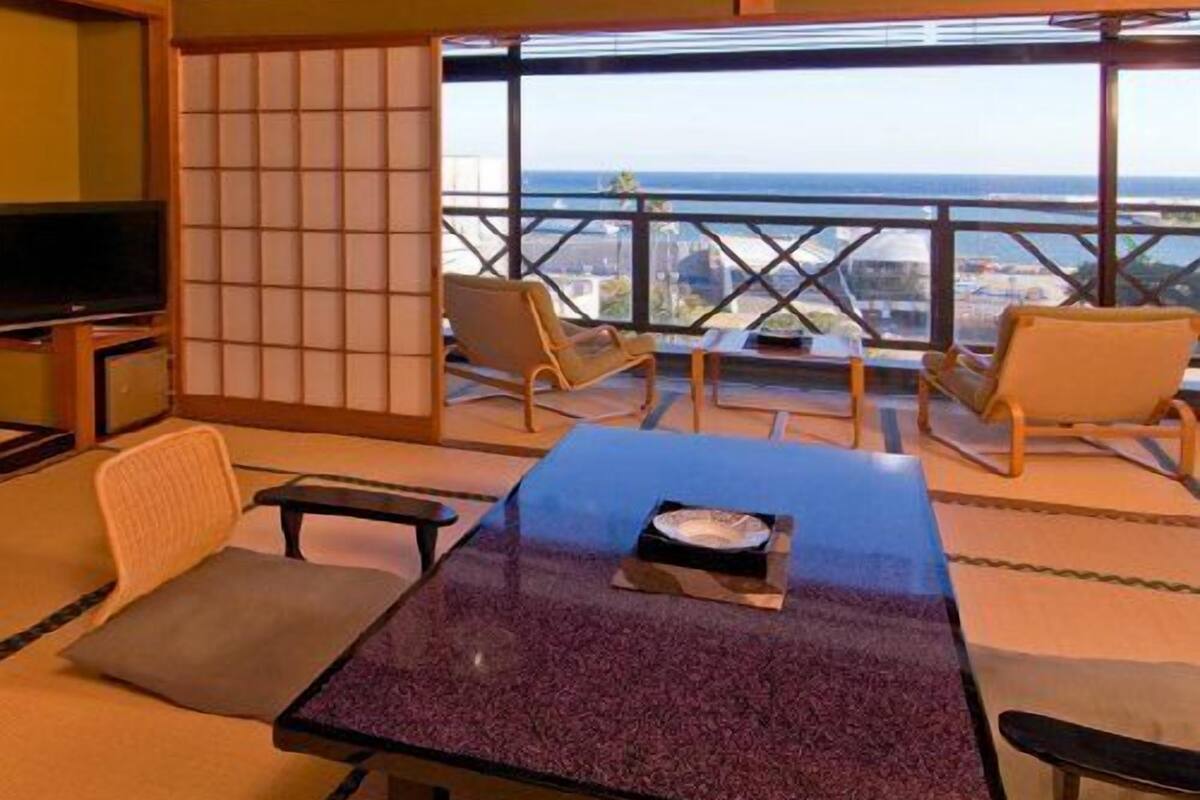 A room with tatami mats, a low table with a bowl, and chairs.
