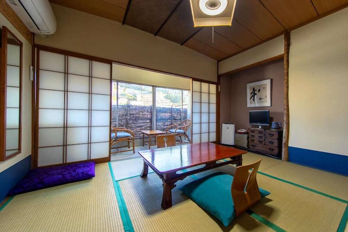 A traditional Japanese room with tatami flooring, a low table, and sliding doors.