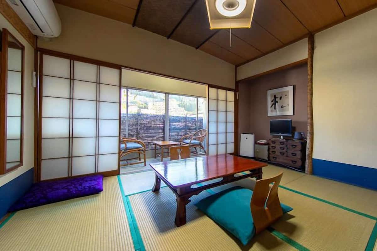 A traditional Japanese room with tatami flooring, a low table, and sliding doors.