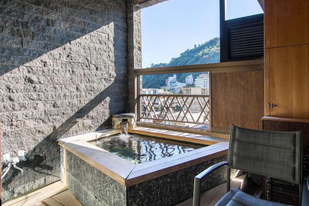 A stone wall, a hot spring, a wooden cabinet, and a view of buildings.