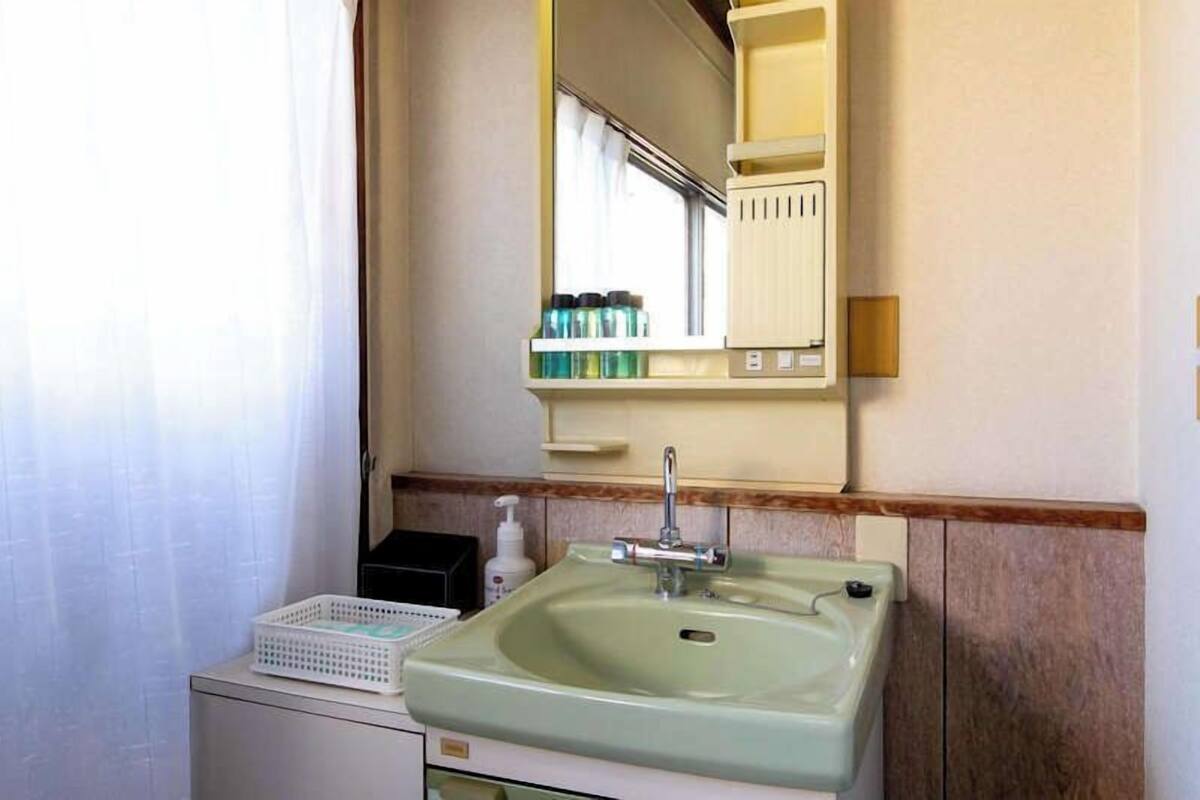 A bathroom with a sink, mirror, and toiletries.