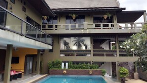 Un immeuble de deux étages doté d’une piscine, de balcons et de plantes en pot.