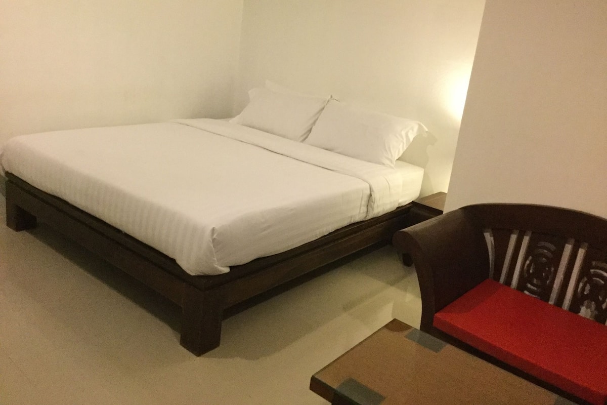 A neatly made bed in a room with a small table and a chair.
