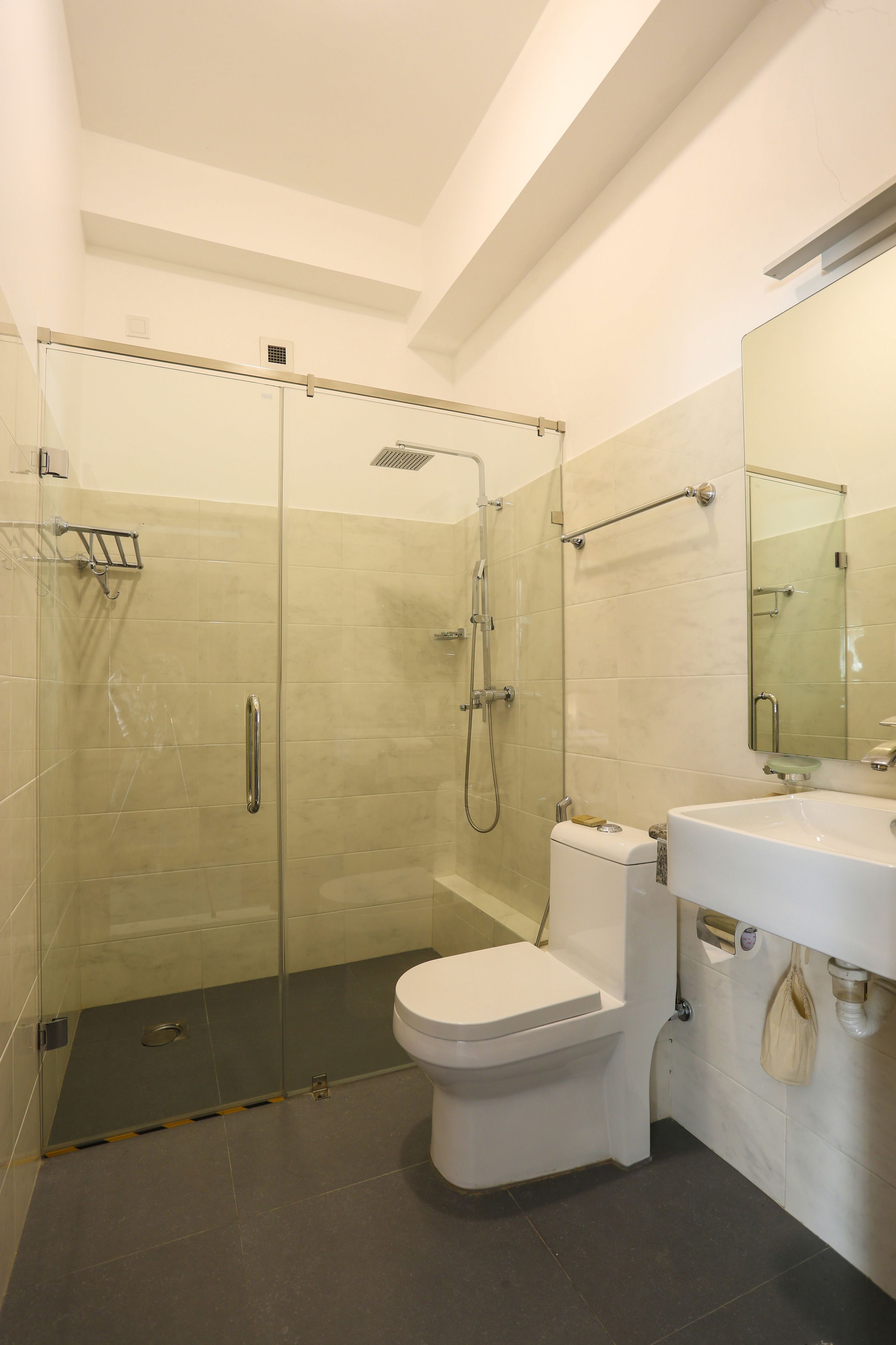A modern bathroom with a glass-enclosed shower, a white toilet, and a sink with a mirror.
