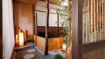 A traditional Japanese interior with tatami flooring, a bamboo plant, and a shoji screen.