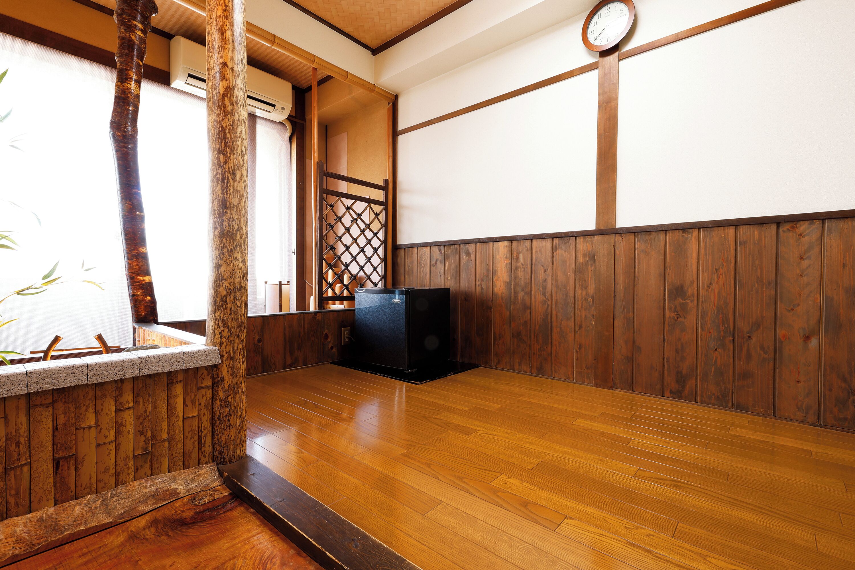 A traditional Japanese room with tatami flooring, a wooden partition, and a clock on the wall.