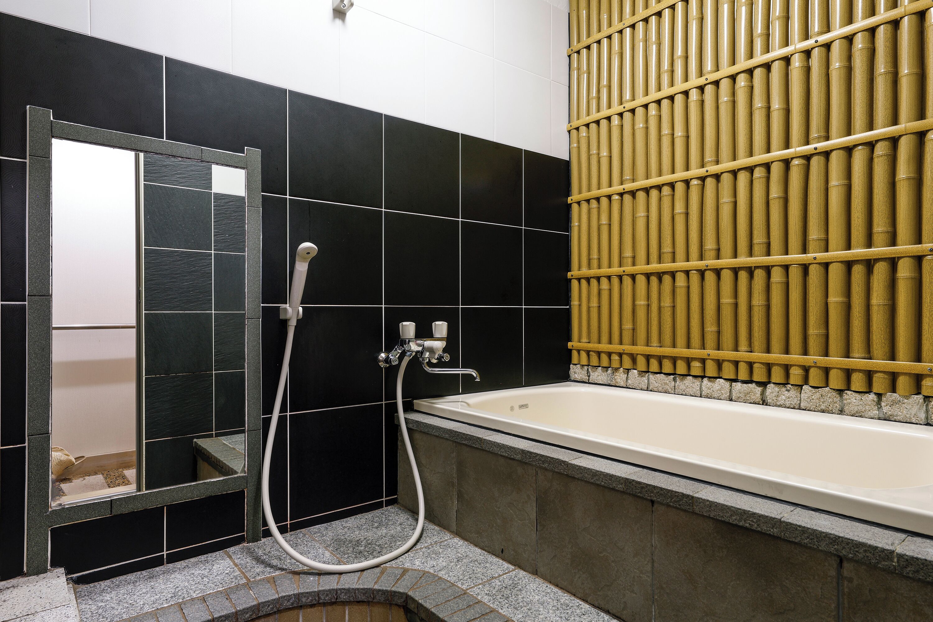 A bathroom with a bathtub, a shower, and a mirror.