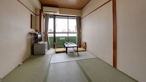 A traditional Japanese room with tatami flooring, a futon bed, a small table, and a television. - Hotel Omiya (Kyoto)