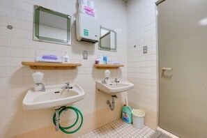 A bathroom with two sinks, a mirror, a towel dispenser, and a hand soap dispenser. - Hotel Omiya (Kyoto)