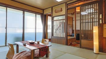 A traditional Japanese room with tatami flooring, a low table with a tea set, and sliding doors leading to another space.