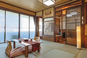 A traditional Japanese room with tatami flooring, a low table with a tea set, and sliding doors leading to another space. - Hotel Omiya (Kyoto)