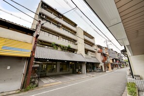 A multi-story building with a ground-floor commercial space, including a closed shop and a visible bicycle. - Hotel Omiya (Kyoto)