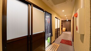 A hallway with sliding doors, a wooden bench, and a red carpet. - Hotel Omiya (Kyoto)