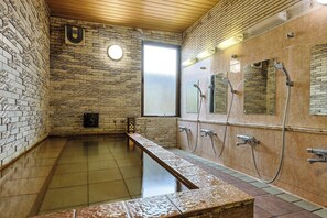 Un cuarto de spa con una bañera grande, una ventana y una pared con diseño de ladrillo.