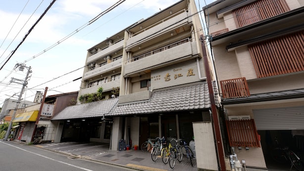 A multi-story building with a tiled roof and a sign indicating it is a hotel. There are bicycles parked outside and a visible entrance. - Hotel Omiya (Kyoto)