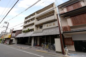 A multi-story building with a tiled roof and a sign indicating it is a hotel. There are bicycles parked outside and a visible entrance. - Hotel Omiya (Kyoto)