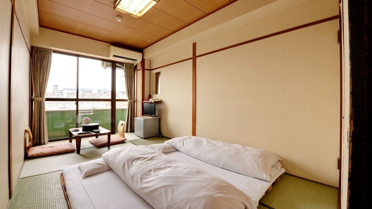 A hotel room with a bed, a small table, a TV, and a window with a view.