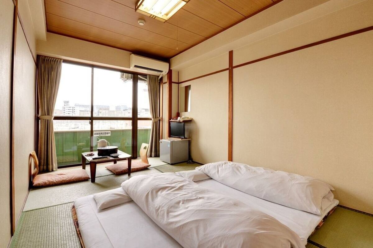 Habitación de hotel con cama, una mesita, televisión y ventana con vistas.