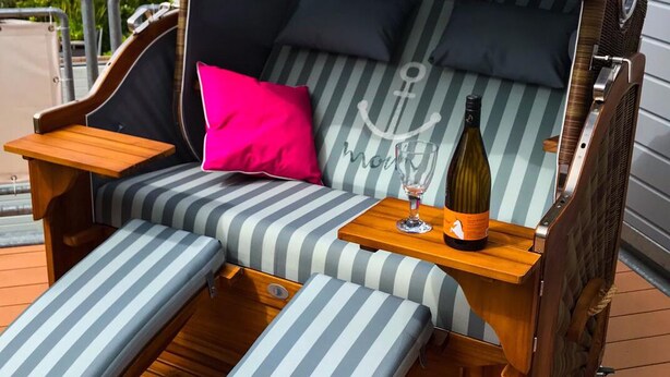 A striped outdoor sofa with a canopy, a wooden table with a bottle, and a pink pillow. - Tradition meets modernity: captain's house on the Friedrichschleuse **** (Carolinensiel-Harlesiel)