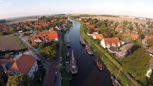 An aerial view of a riverside town with houses, boats, and a bridge. - Tradition meets modernity: captain's house on the Friedrichschleuse **** (Carolinensiel-Harlesiel)