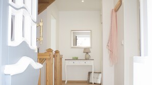 A hallway with a wooden floor, a white door, a wooden staircase, a console table with a lamp, and a framed picture on the wall. - Tradition meets modernity: captain's house on the Friedrichschleuse **** (Carolinensiel-Harlesiel)