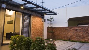 Ein modernes Haus mit Glastür, Backsteinwand und einem kleinen Garten.