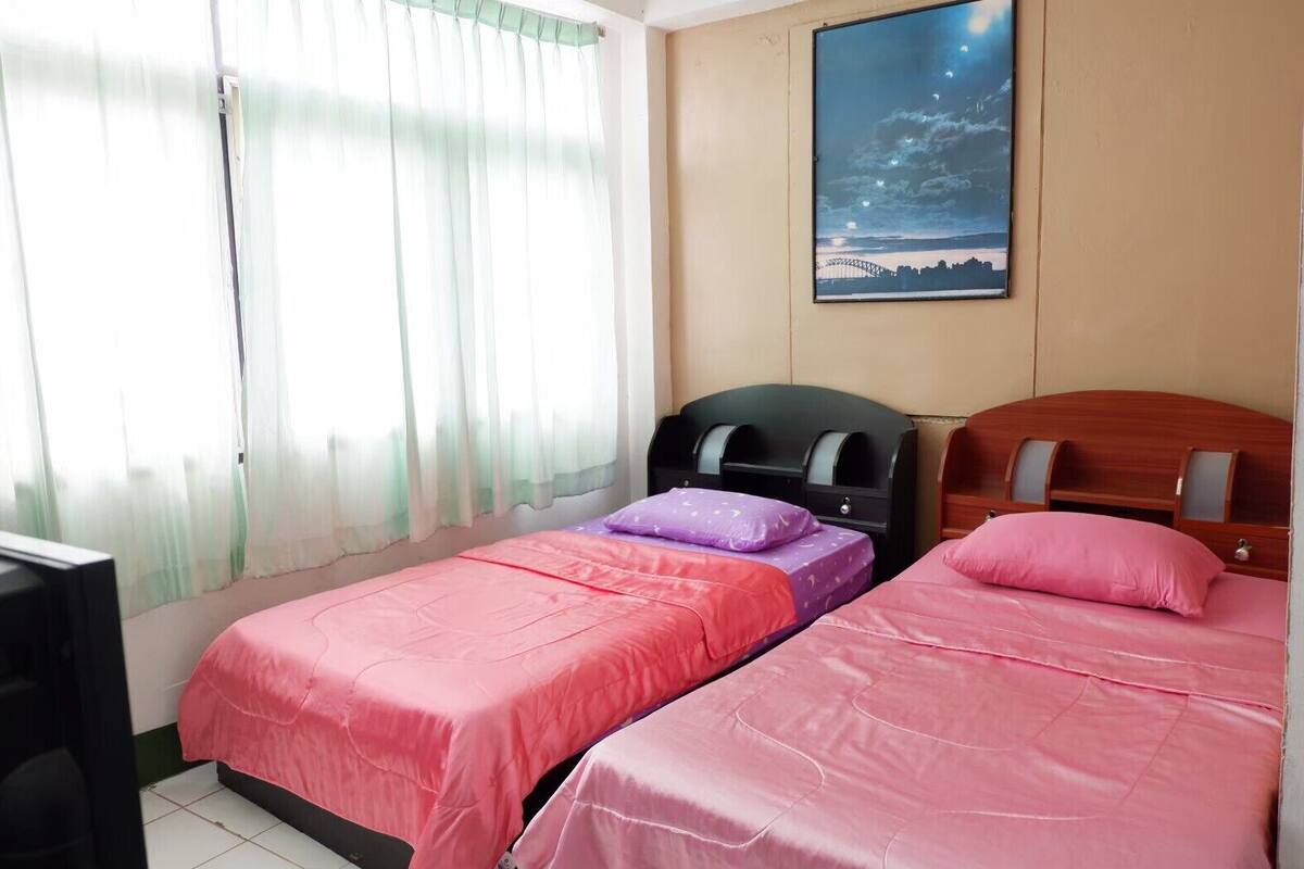 Una habitación con dos camas, televisión y un cuadro de un puente.