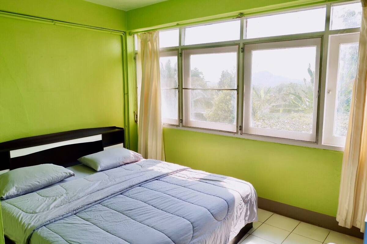Una habitación con una cama, una ventana con cortinas y vistas al exterior.