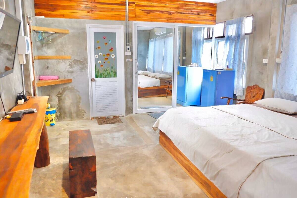 Un dormitorio con cama de madera, un escritorio, una silla, un armario y una puerta con diseño floral.