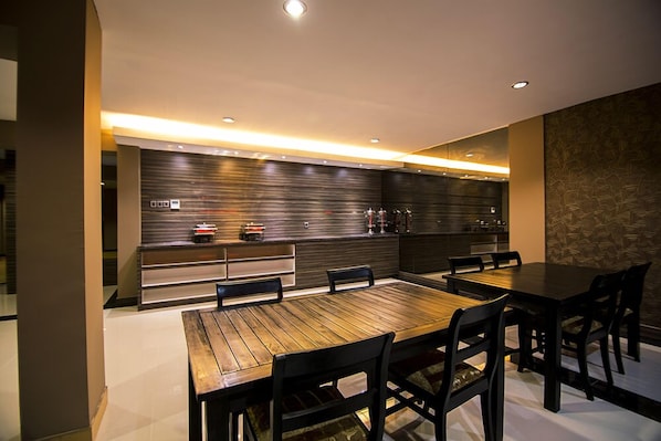 A modern kitchen with a wooden dining table and chairs, built-in appliances, and a sleek backsplash.