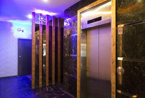 An elevator with a digital display, a marble wall, and a wooden panel design.