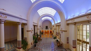 A grand hotel lobby with a high ceiling, arched windows, and a patterned floor. - Charmant T2, hypercentre, calme, terrasse, parking, commerces (Bagnères-De-Luchon)