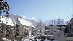 A snow-covered residential area with multi-story buildings, a staircase, and a clear sky. - Charmant T2, hypercentre, calme, terrasse, parking, commerces (Bagnères-De-Luchon)