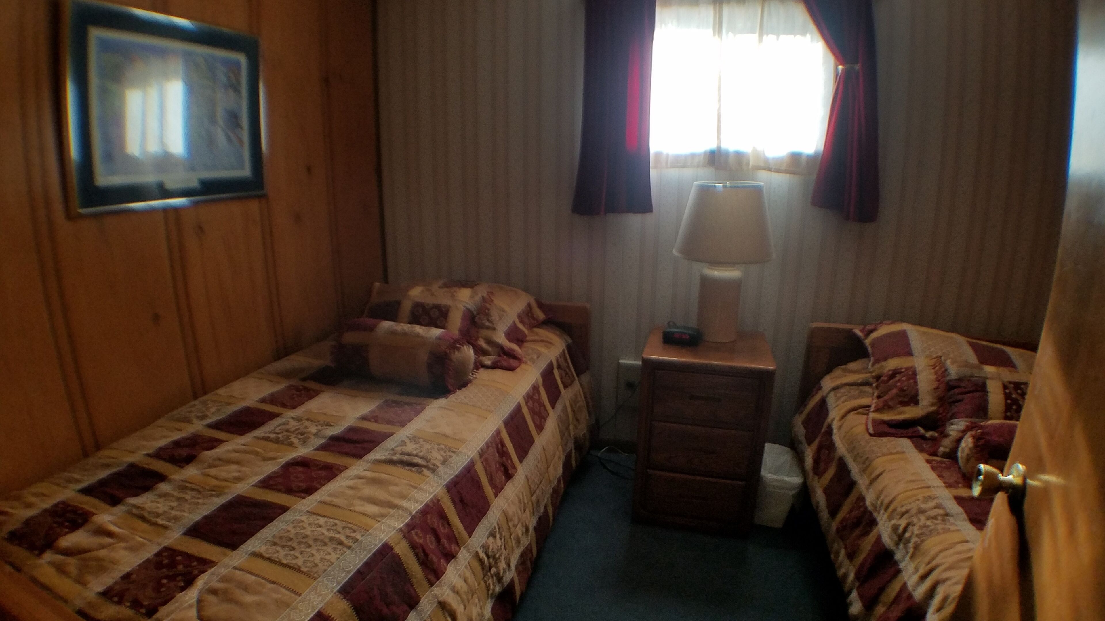 A hotel room with a single bed, a nightstand with a lamp, and a small table.