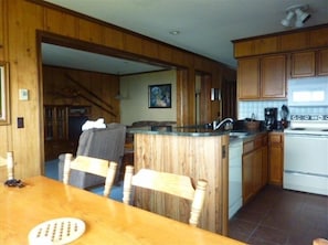 A kitchen with wooden cabinets, a stove, and a dining area with a table and chairs. - Stay a week this time for 20% discounts!!  A+ Location. Amazing Views. So cozy!! (Dunmore)