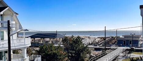 Una zona residencial costera con una casa blanca destacada, un paseo techado y vista al océano.