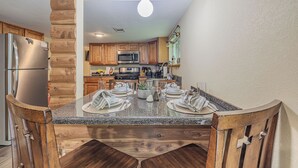 A kitchen with wooden cabinets, a granite countertop, and a dining area with a table set for four.