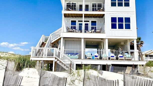 A multi-story beachfront house with balconies, a covered deck, and beach chairs. - Gulf front, North Cape, huge outdoor lounge, fenced pet area!!!! (Port St Joe)