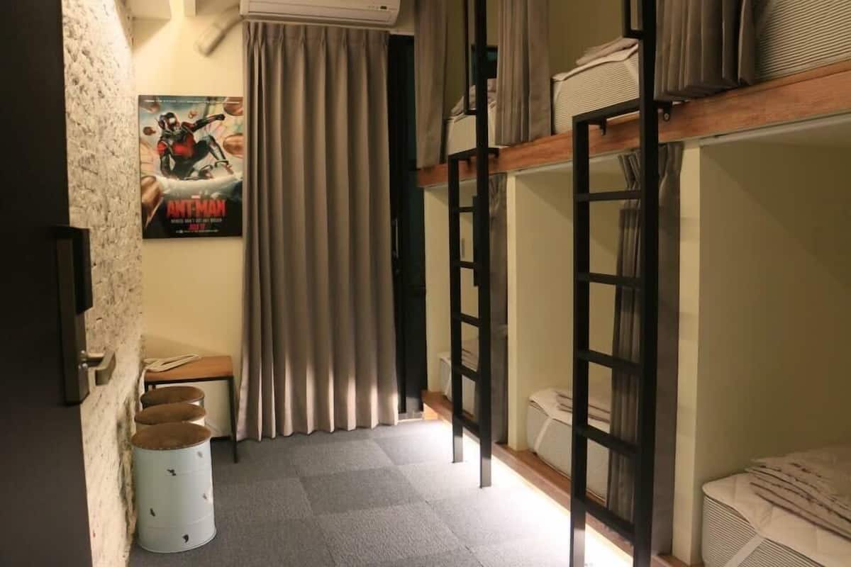 Una habitación con literas, un cartel en la pared, una mesita y una cortina.