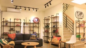 Una sala de estar con un sofá, dos sillones, una mesa de centro y estantes con diversos objetos.