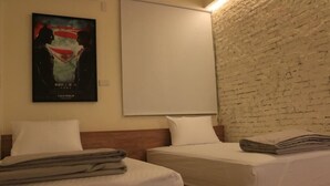 Una habitación de hotel con dos camas, una pared de ladrillo y un cartel en la pared.