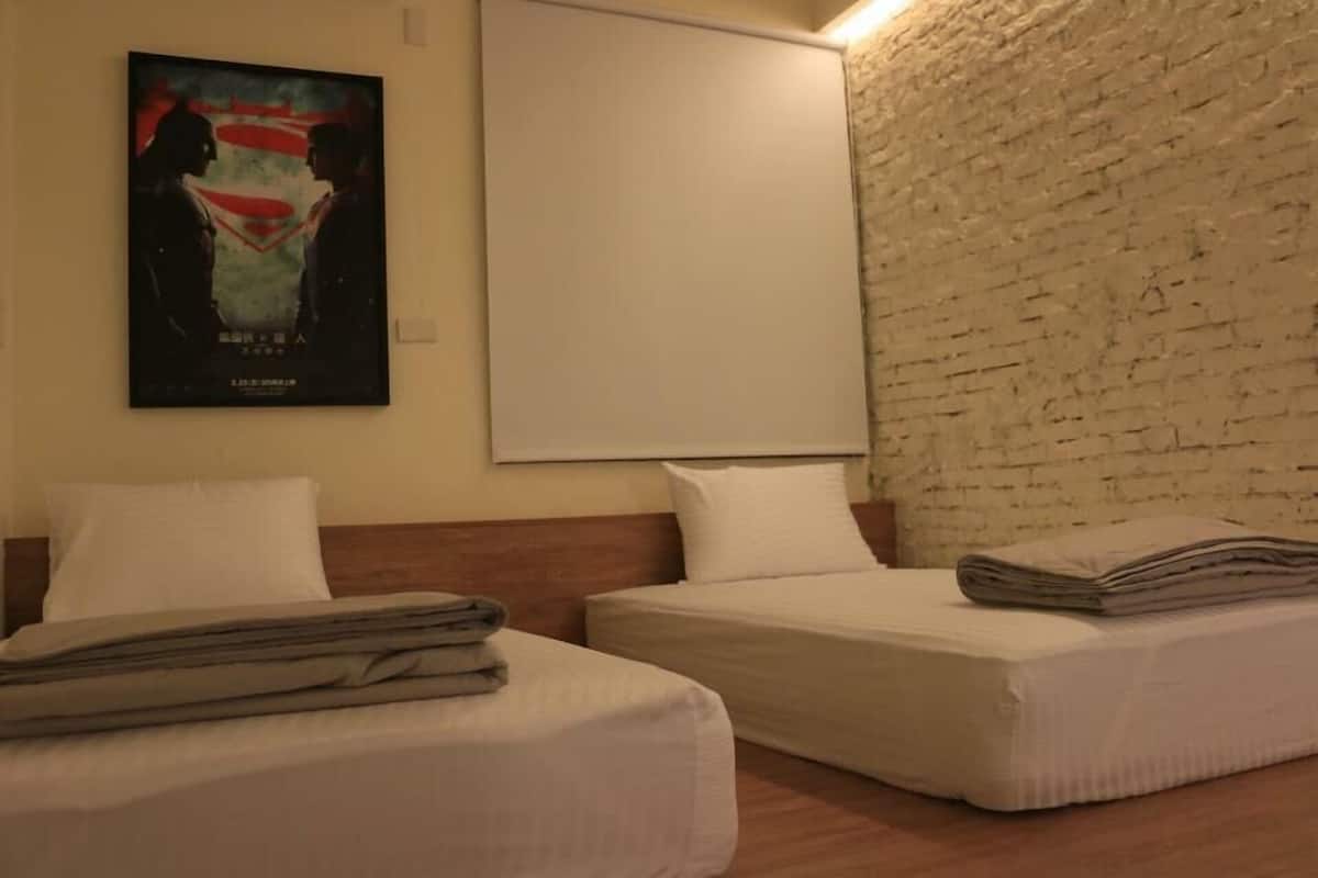 Una habitación de hotel con dos camas, una pared de ladrillo y un cartel en la pared.
