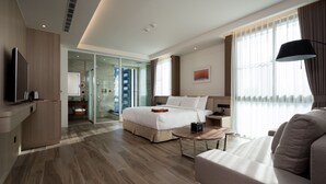 A modern hotel room with a large bed, a sofa, a TV, and a glass door leading to a balcony. - Hsing Fu Hotel (Jiaoxi)