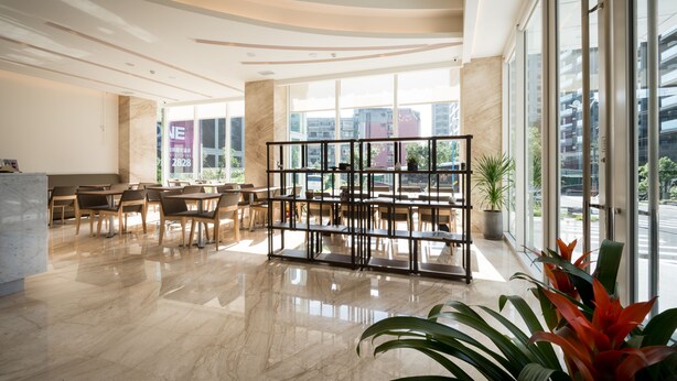 A spacious lobby with a marble floor, a reception desk, and a seating area with tables and chairs. - Hsing Fu Hotel (Jiaoxi)
