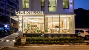 A modern hotel with a glass facade, visible interior seating, and a staircase leading to the entrance. - Hsing Fu Hotel (Jiaoxi)