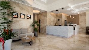 A modern lobby with a reception desk, a sofa, a coffee table, and potted plants. - Hsing Fu Hotel (Jiaoxi)