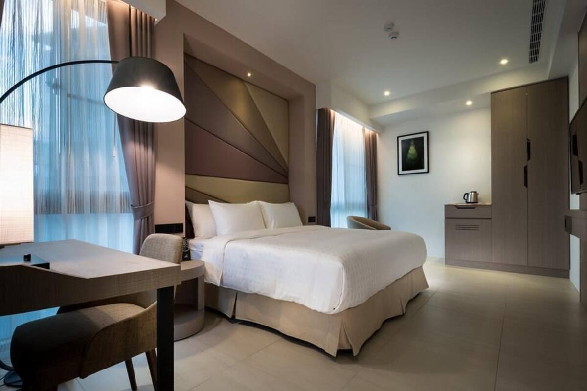 Une chambre d’hôtel moderne équipée d’un lit, d’un bureau, d’une chaise et d’un téléviseur.
